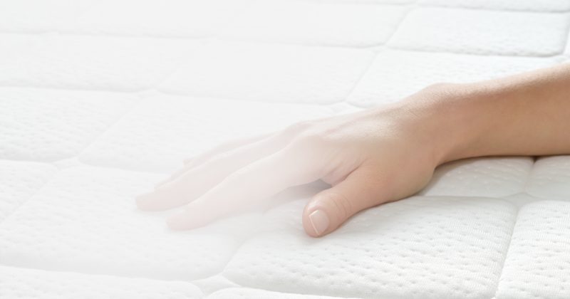 Hand liegt auf Matratze